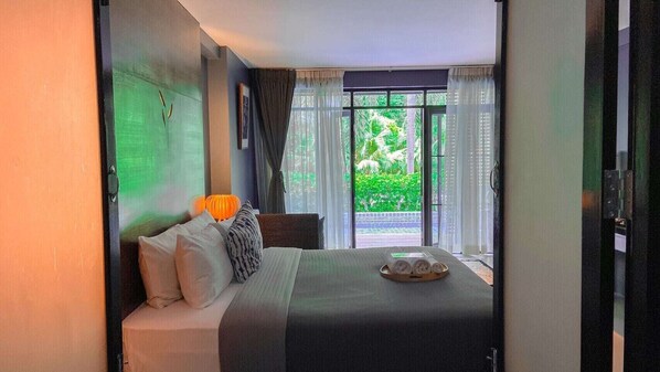 A hotel room with a bed, a bedside lamp, and a view of greenery outside. - The Bihai Hua Hin (Hua Hin)