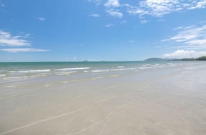 Une plage avec un ciel dégagé et une mer calme.