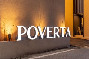 A building entrance with the word 'POVERTA' illuminated on a wall. - poverta-stay hotel (Gyeongju)