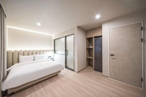 Une chambre d’hôtel moderne avec un grand lit, une armoire et un dressing.