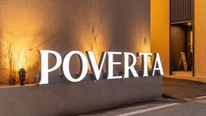 Un letrero con la palabra "POVERTA" iluminada sobre una pared con textura.