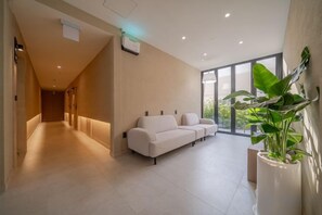 A modern interior with a hallway leading to a seating area, a large window, and a potted plant. - poverta-stay hotel (Gyeongju)