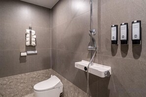 A modern bathroom with a toilet, a shower, and three hand sanitizer dispensers on the wall. - poverta-stay hotel (Gyeongju)