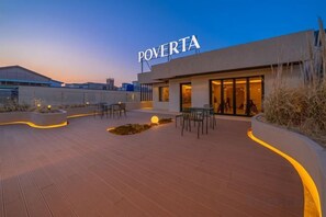 A modern building with the name 'POVERTA' on the facade, outdoor seating area, and a paved walkway. - poverta-stay hotel (Gyeongju)