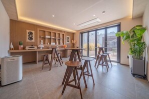 A modern kitchen with a bar area, wooden stools, and a large window. - poverta-stay hotel (Gyeongju)