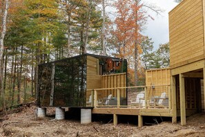 Une cabane en bois dotée d’une terrasse, entourée d’arbres aux feuilles d’automne.