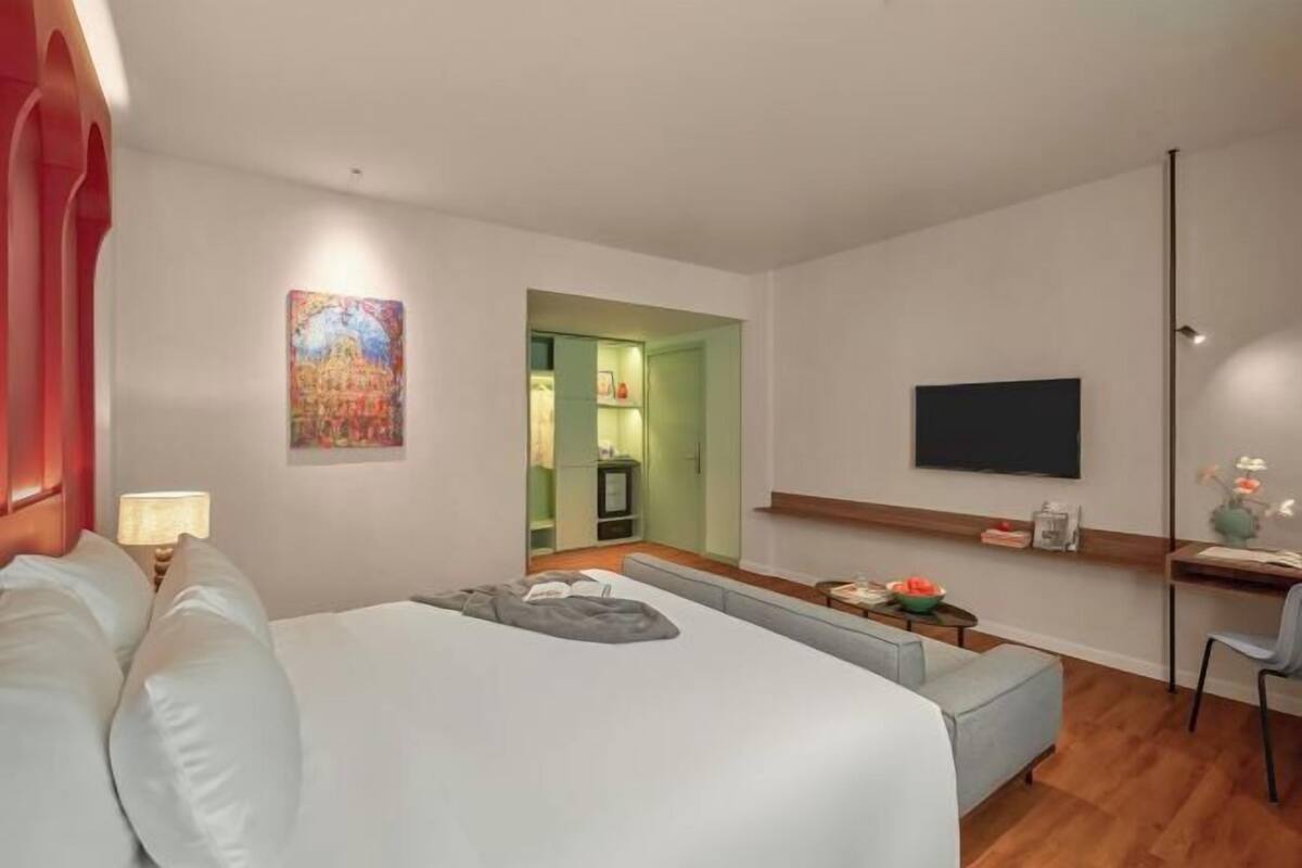 Une chambre d’hôtel moderne équipée d’un lit, d’un bureau, d’une télévision et d’un tableau au mur.