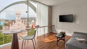 Una habitación moderna con un ventanal grande, un televisor de pantalla plana, una mesa de comedor y un sofá.