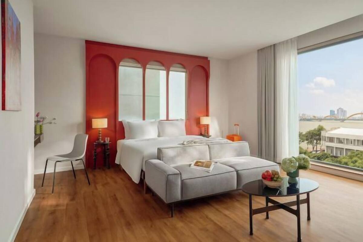 Une chambre d’hôtel comprenant un lit, un canapé, une table à manger, une chaise et une vue sur le paysage urbain.