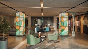 Un vestíbulo moderno con una zona de estar central, un mostrador de recepción e una gran instalación de arte abstracto.
