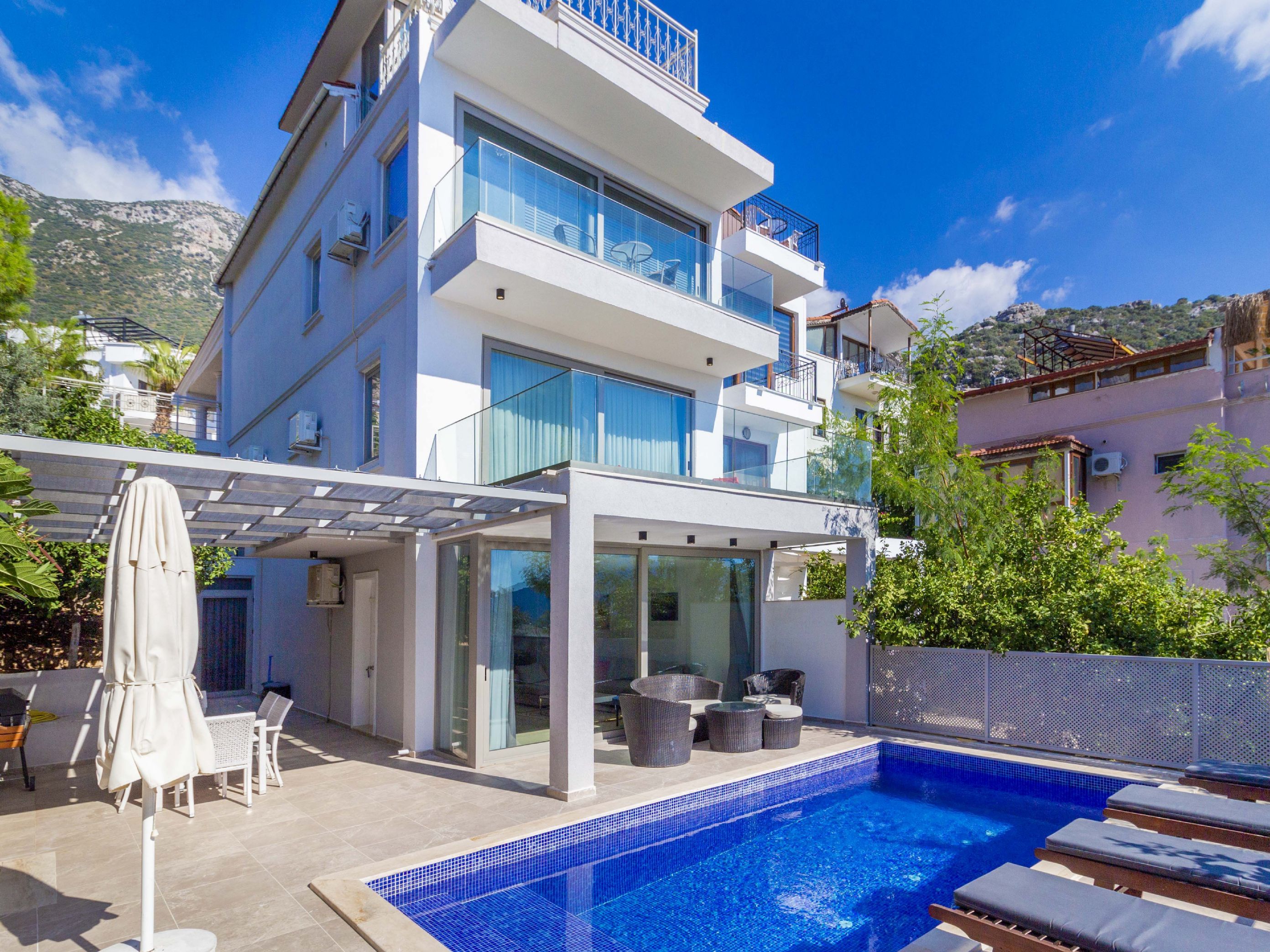 A modern multi-story building with a rooftop terrace, a swimming pool, and outdoor seating.