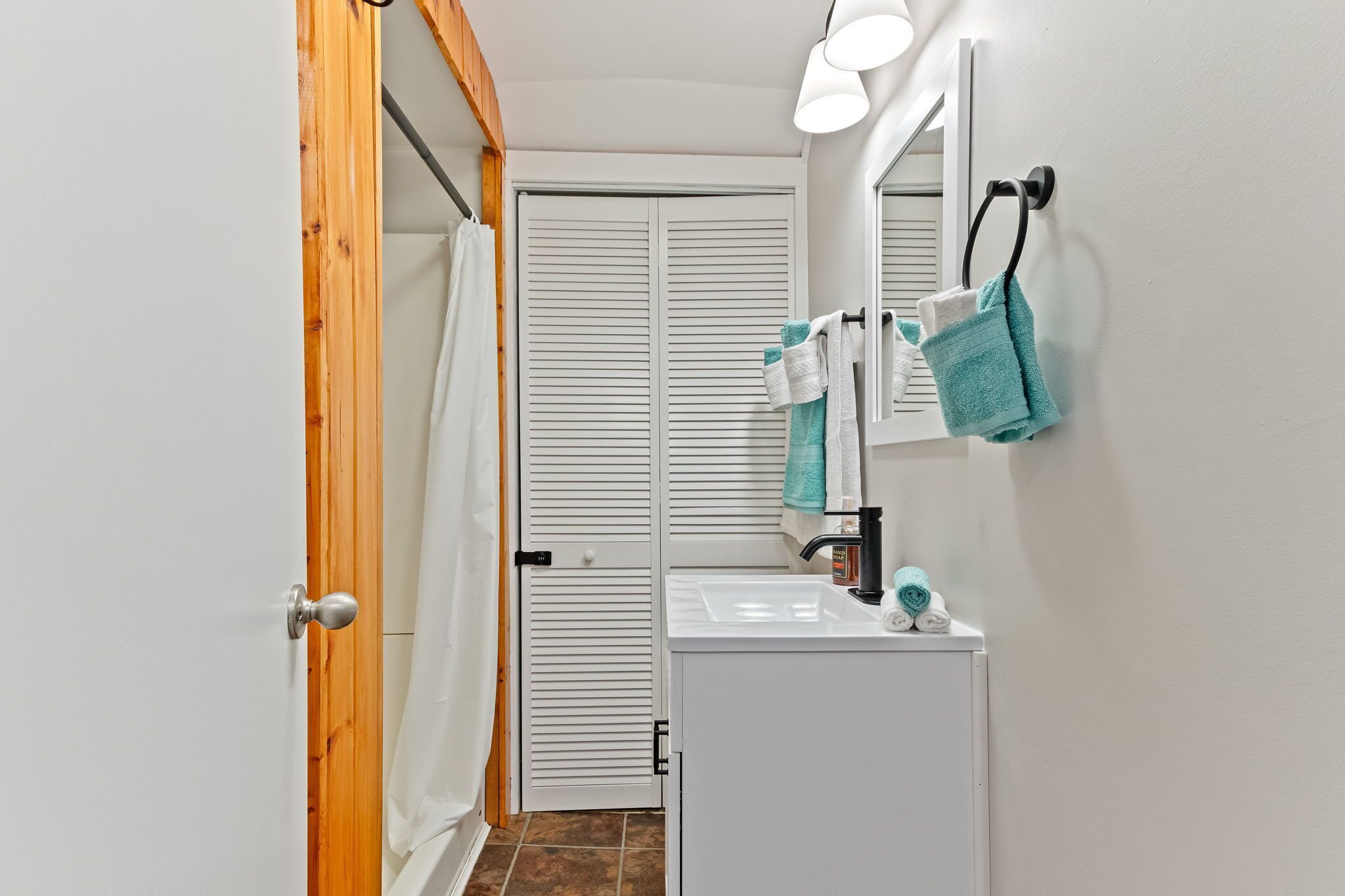 A bathroom with a white sink, a mirror, and a towel rack.