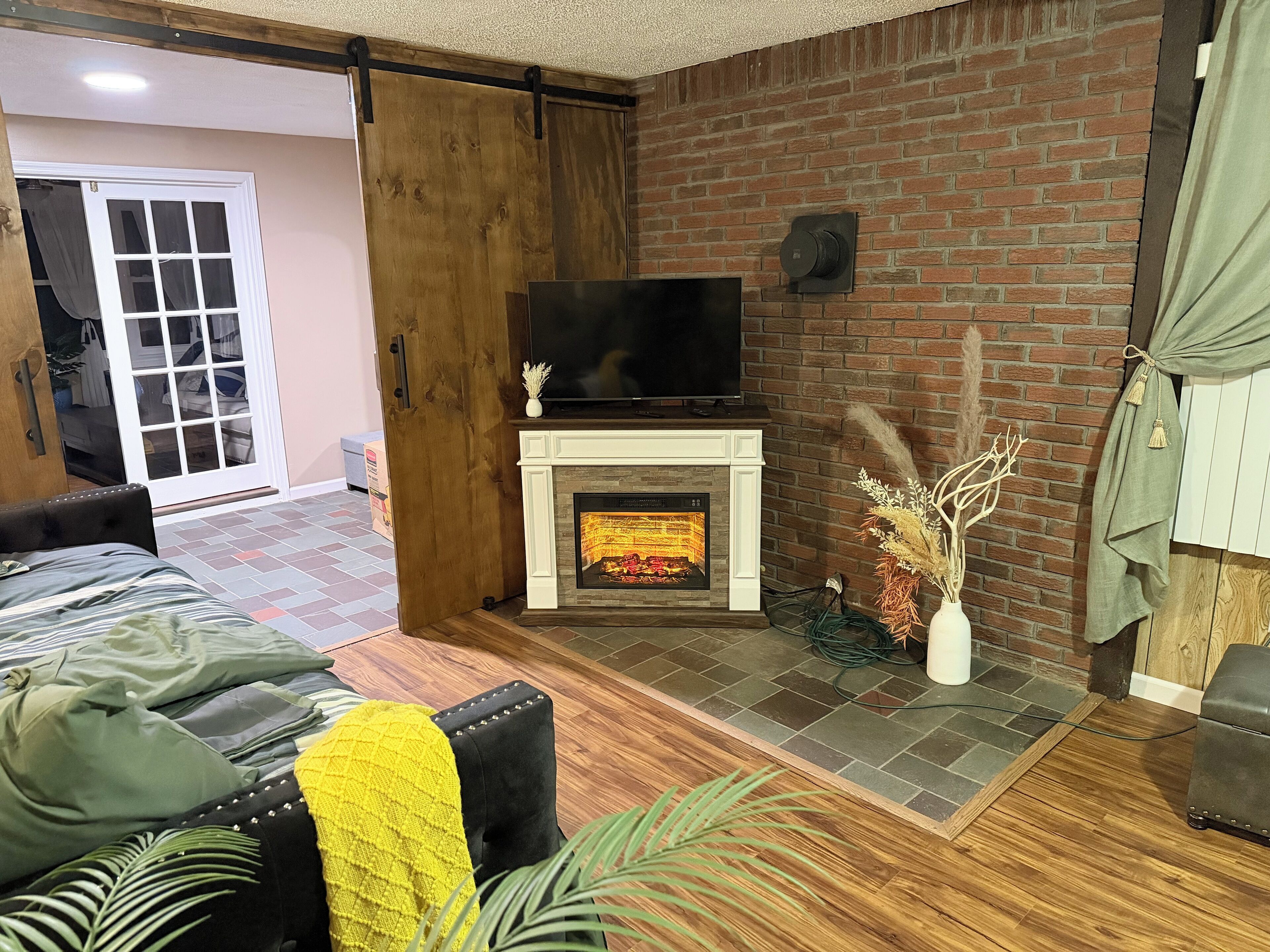 A living room with a fireplace, a television, and a sliding door leading to a balcony.