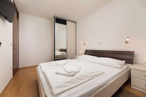 A hotel room with a bed, bedside tables, a mirror, and a television. - Villa Maravilla (Kvarner - Jadranovo) (Jadranovo)