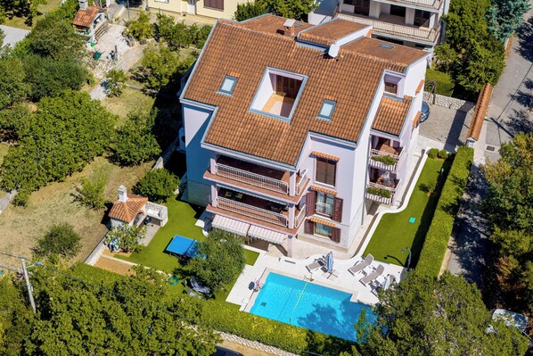 Un immeuble résidentiel à plusieurs étages doté d’une terrasse sur le toit, d’une piscine et d’un jardin bien entretenu.