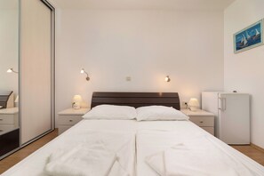 A hotel room with a bed, two bedside tables with lamps, a small refrigerator, and a painting on the wall. - Villa Maravilla (Kvarner - Jadranovo) (Jadranovo)