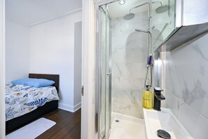 Ein Schlafzimmer mit Bett, Nachttisch und einem Badezimmer mit Dusche und Waschbecken.