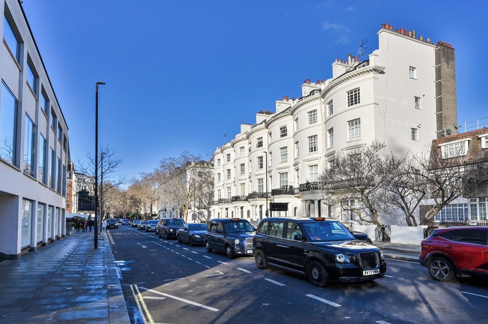 A street lined with historic buildings, parked cars, and a sidewalk.