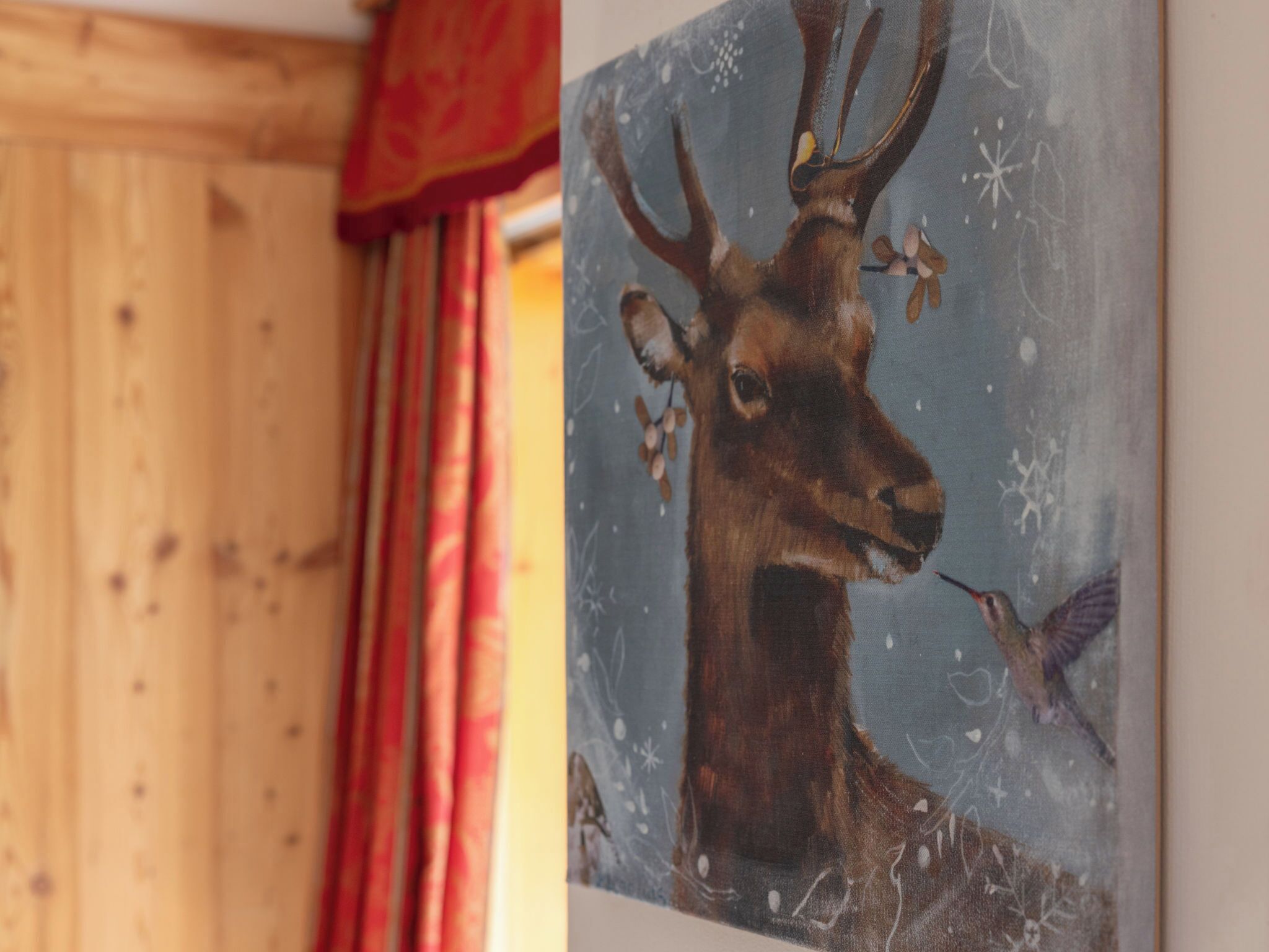 Ein Gemälde zeigt einen Hirsch mit Geweihen und einen Kolibri an einer Wand.