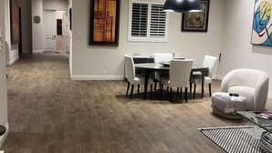 A modern dining area with a round table and chairs, a black pendant light, and a white armchair. - Elegant Private 2-Bedroom Ensuite Condo with Expansive Living and Dining Areas (Rancho Mirage)