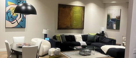 Ein modernes Wohnzimmer mit Essbereich, mit rundem Tisch, Stühlen, einer Couch und einem Couchtisch.