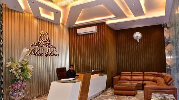 A reception area with a modern design, featuring a reception desk, a sofa, and a decorative wall with the text "Blue Lane". - Hotel Blue Stone (Kanpur)