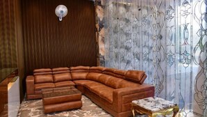 A modern living room with a sectional sofa, a coffee table, and a patterned wall. - Hotel Blue Stone (Kanpur)