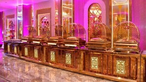A row of ornate, golden trophy-like structures with intricate designs, set against a backdrop of pink and purple lighting. - Hotel Blue Stone (Kanpur)