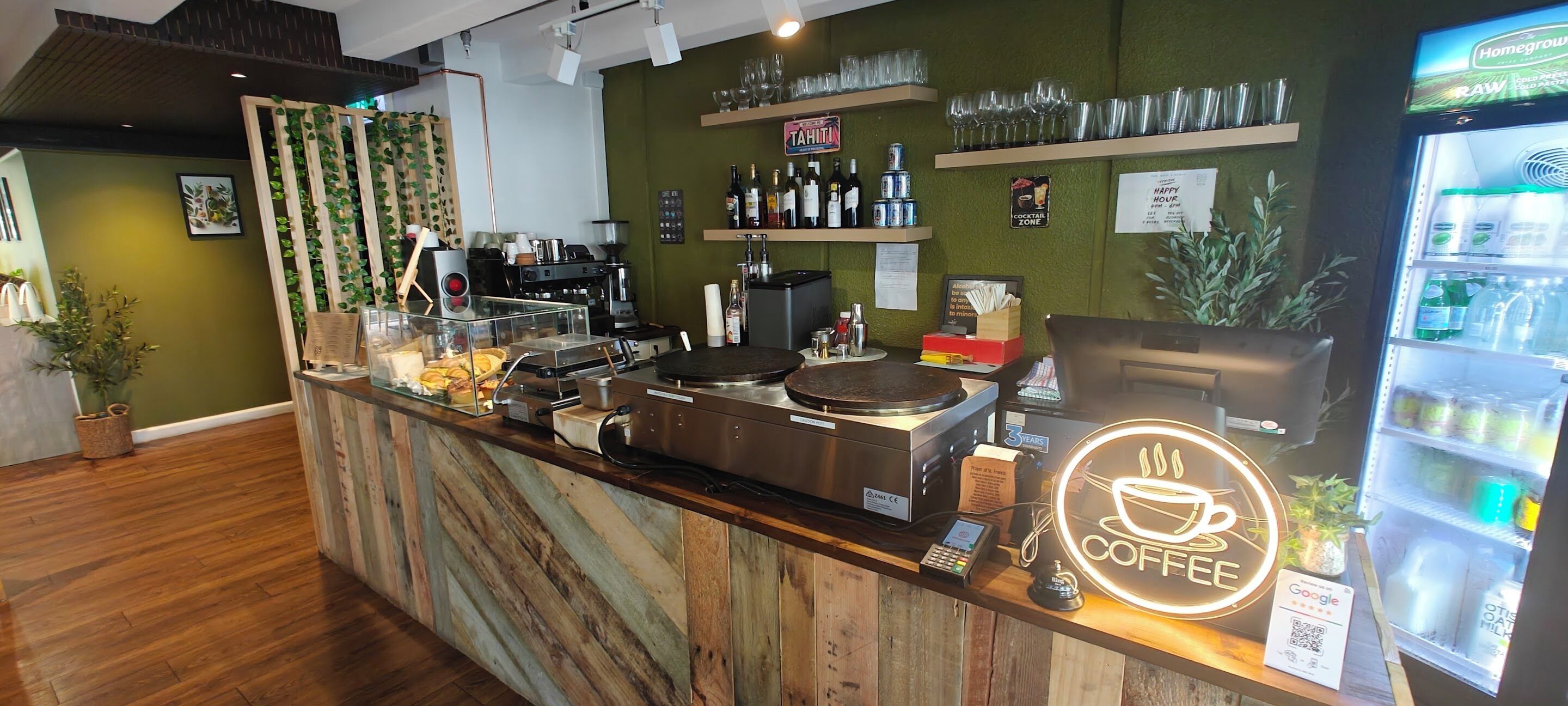 Ein Café mit Holztresen, Kaffeemaschinen und einem Neonzeichen.