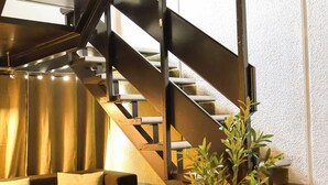 A modern interior with a staircase, a sofa, and a plant. - Noa Hotel (Auckland)