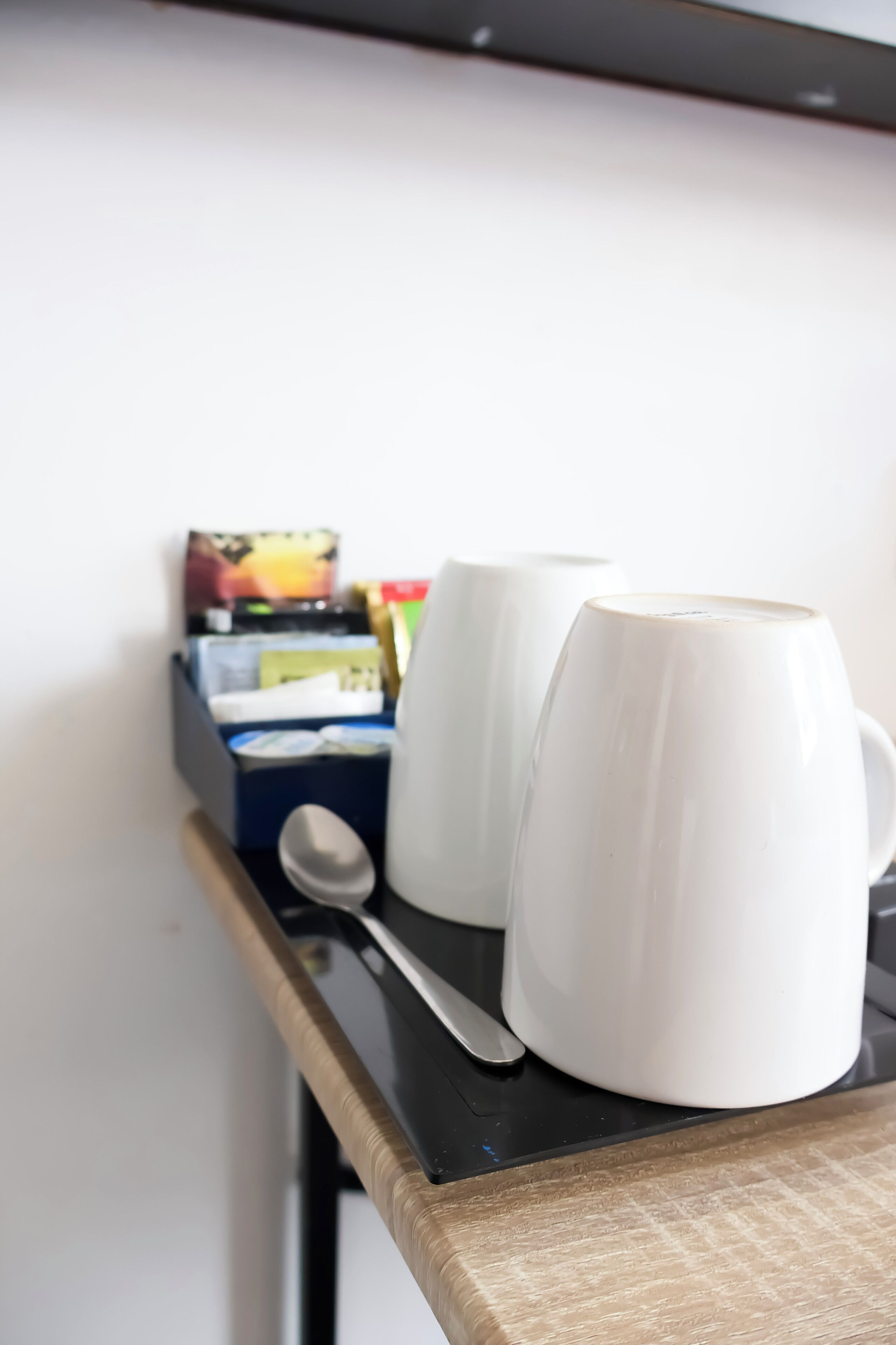 A kitchen counter with two white mugs, a spoon, and a box of tissues.