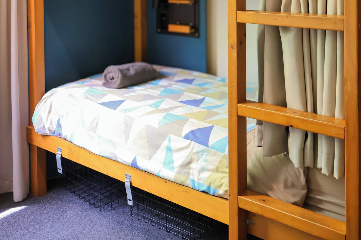 Ein Etagenbett mit einem Bett unten und einem Bett oben. Auf dem Bett unten liegt ein Kissen, auf dem Bett oben eine Decke.