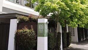 A modern hotel building with a sign indicating a parking area and reception. - Noa Hotel (Auckland)