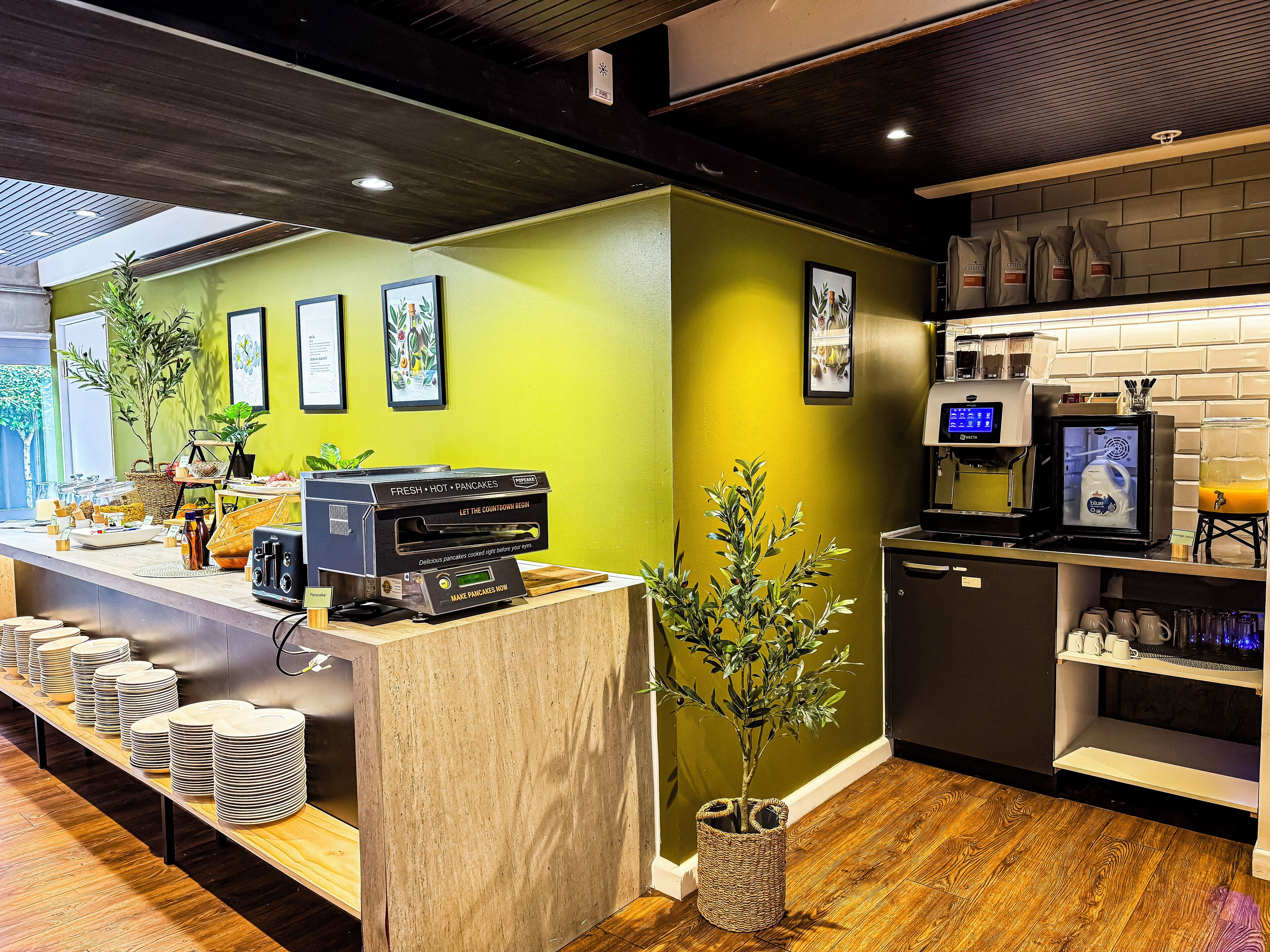 A breakfast bar with a coffee machine, a digital screen, and a plant.
