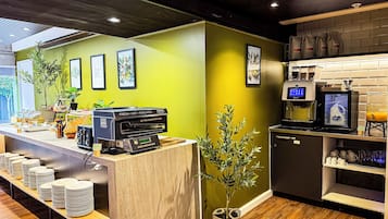 A breakfast bar with a coffee machine, a digital screen, and a plant.