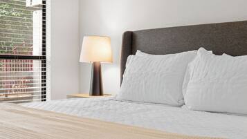 Ein ordentlich bezogenes Bett mit weißen Leinentüchern, einem dunklen Kopfteil und einer Nachttischlampe.