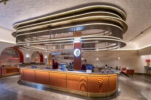 A modern hotel lobby with a curved reception desk, a bar area, and a seating space. - Beijing Manxin Hotel Tiananmen Square (Beijing)