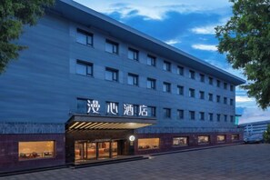 Un hotel amb façana moderna, diverses plantes i una entrada destacada amb cartelleria il·luminada.
