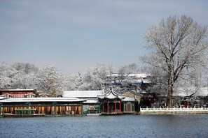 A traditional building with a tiled roof and a wooden structure in front, located beside a body of water.