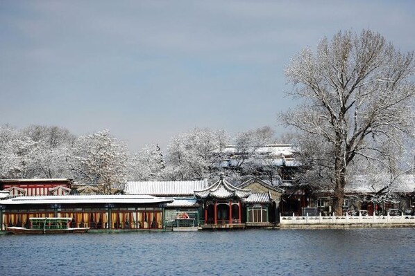 A traditional building with a tiled roof and a wooden structure in front, located beside a body of water.