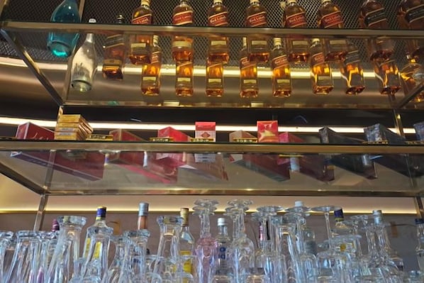 A bar area with shelves of bottles and glasses.
