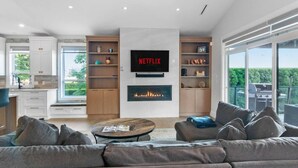 Een moderne woonkamer met een open haard, een grote flatscreen televisie en een balkon met uitzicht.