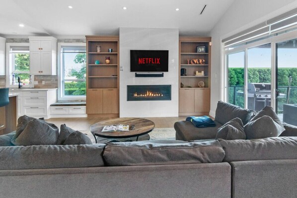 Una sala de estar moderna con chimenea, un televisor de pantalla plana grande y un balcón con vistas.