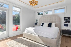 Un dormitorio moderno con una cama grande, varias ventanas y vistas al exterior.