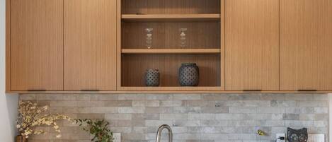 Een keuken met houten kastjes, een betegelde spatwand, een spoelbak en decoratieve objecten.