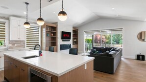 Een moderne keuken met een groot eiland, houten kastjes en hanglampen.