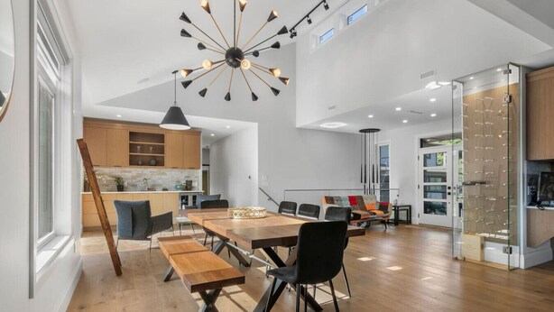 Een moderne keuken met houten kastjes, een eethoek met een houten tafel en banken, en een grote kroonluchter.