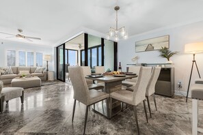 Ein modernes Wohnzimmer mit Essbereich, großen Fenstern und Deckenventilator.