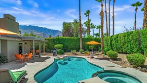 A swimming pool with a hot tub, surrounded by palm trees and a mountain view. - Desert Gem - Bold Design, Poolside Fun, Spa, BBQ & Views (Palm Springs)