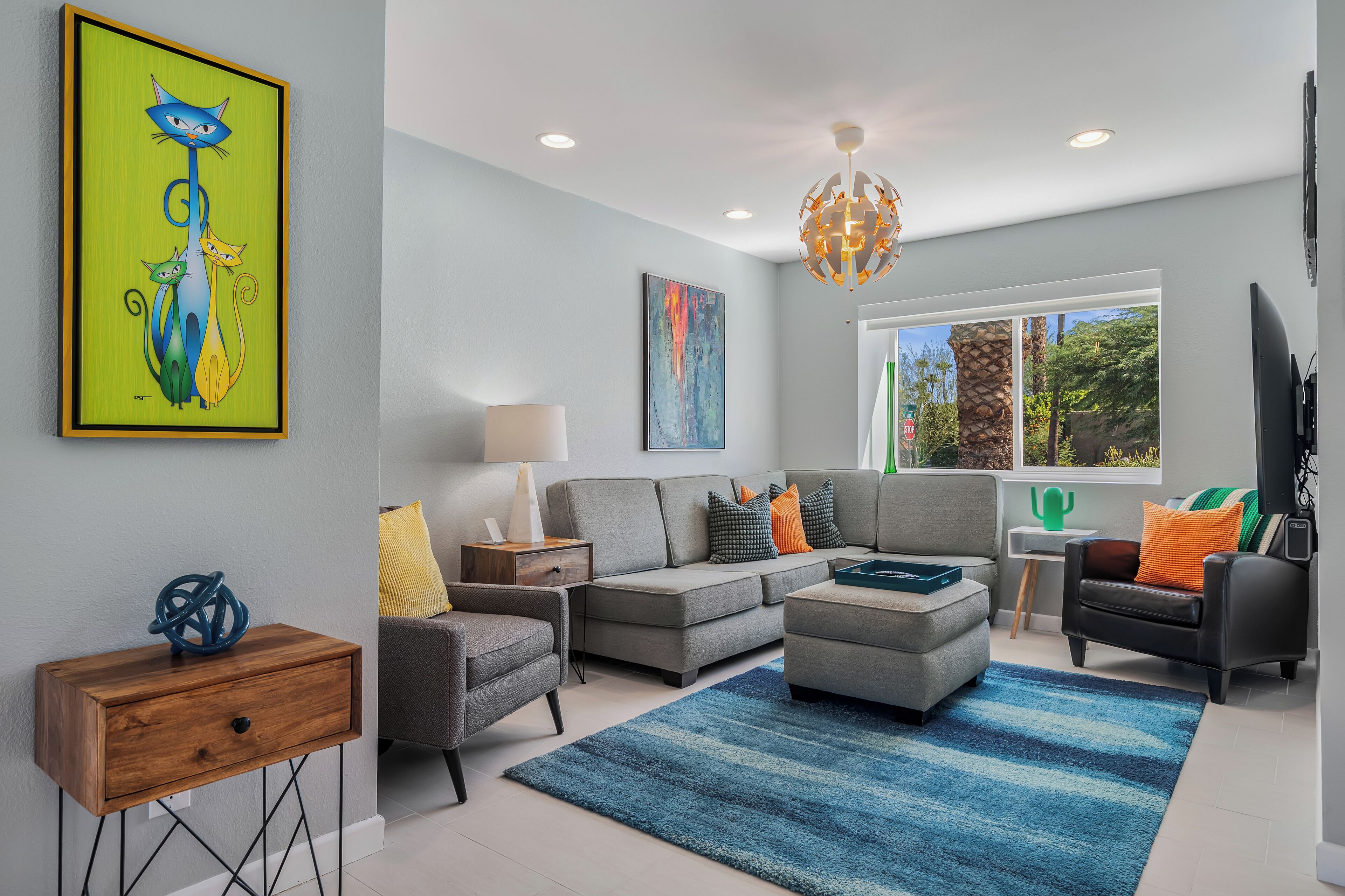 A modern living room with a grey sofa, a blue rug, and a wooden side table.